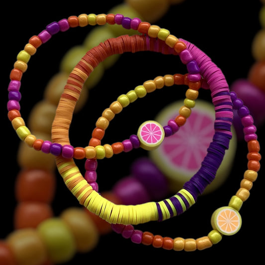 Set of three colorful handmade bracelets with fruit accents.

Sunset-inspired bracelet stack featuring yellow, orange, pink, and purple beads.

Handcrafted summer bracelet set with vibrant hues and playful designs.
